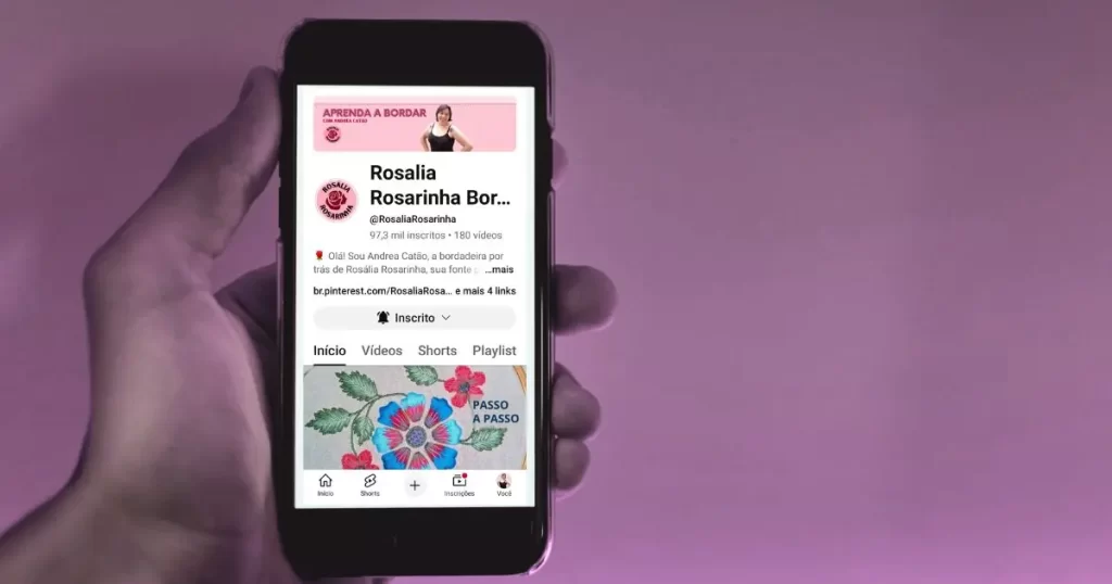canal rosalia rosarinha no youtube 2 uma mão segurando um smartphone com a imagem da capa do canal de bordado livre “rosália rosarinha bordado” no youtube para ilustrar uma chamada do site agulhas da resistência subvertendo linhas e pontos sobre artesanato