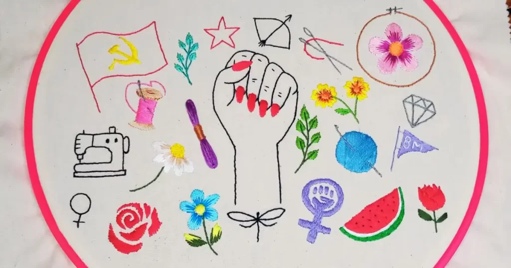 bordado em tecido de algodão em um bastidor de plástico com vários símbolos para o banner do site agulhas da resistência para a série manifesto bordado, criado e produzido pela artesã andrea catão. são bordados de desenhos de um punho feminino erguido, flores, folhas, como rosas e margarida, espelho de vênus, símbolo feminista, bandeira comunista, novelo de linha, carretel, agulhas, libélula, estrela etc