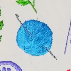 novelo de linha e uma agulha bordados em tecido de algodão