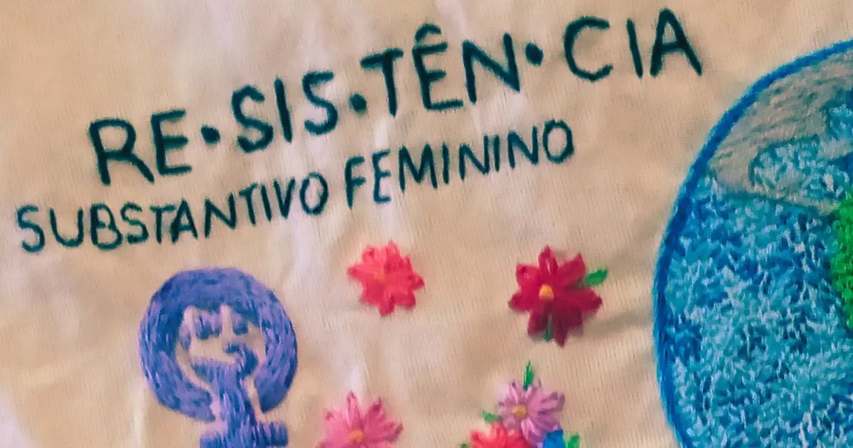 Detalhe de bordado à mão com símbolo feminista e a palavra resistência, usado como imagem de capa de um texto sobre o 8 de março