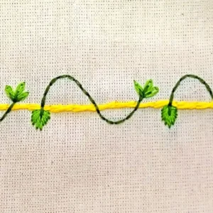 bordado à mão de um barrado de pano de prato bem simples com folhinhas e galhos