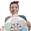 a jornalista e artesã andrea catão segurando um bordado feito por ela em um bastidor de madeira