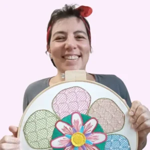 a jornalista e artesã andrea catão segurando um bordado feito por ela em um bastidor de madeira