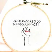 bordado à mão em moldura de bastidor de madeira para o dia primeiro de maio, dia do trabalhador, com a frase "trabalhadores do mundo, uni-vos" com um punho erguido, criado pela artesã andrea catão