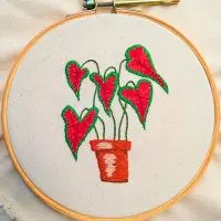 bordado à mão com folhagem de caladium dentro de um vaso, criado pela artesã Andrea Catão