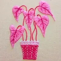 bordado à mão com folhagem de caladium dentro de um vaso totalmente em tons rosa, criado pela artesã Andrea Catão