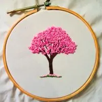 bordado à mão de um ipê rosa em nó francês, criado pela artesã Andrea Catão