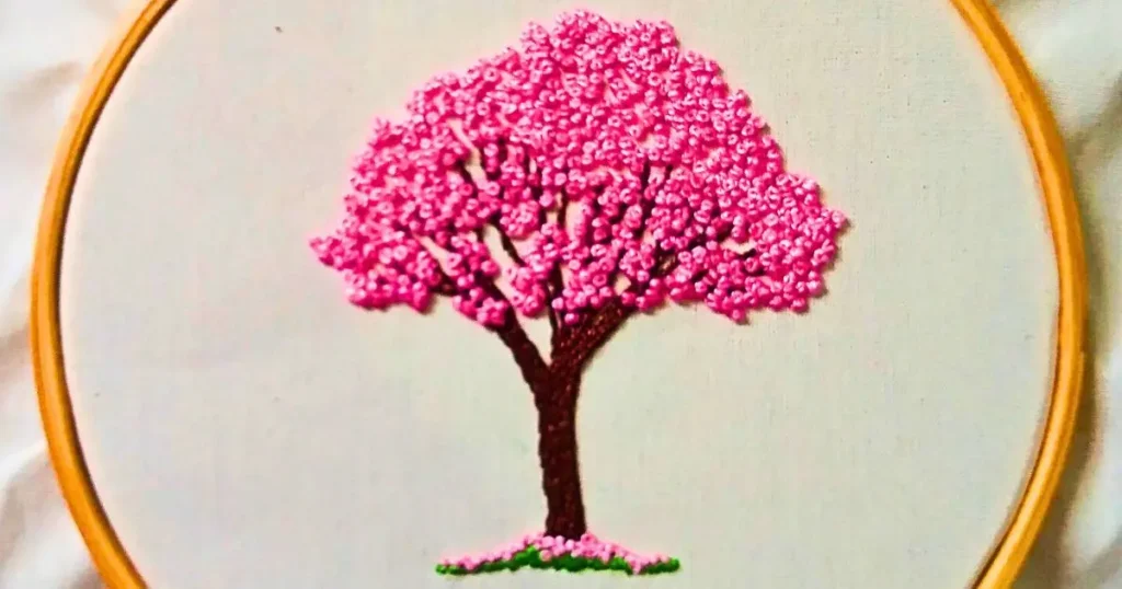 bordado à mão de um ipê rosa em nó francês, criado pela artesã Andrea Catão. bordado em algodão cru com moldura de bastidor de madeira