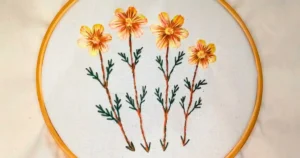 quatro flores amarelas bordadas à mão em ponto cheio. criado pela artesã andrea catão para o canal rosália rosarinha
