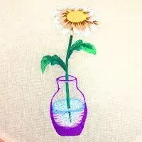 margarida em vaso bordada à mão em pintura de agulha. peça produzida pela artesã andrea catão para o canal rosália rosarinha bordado