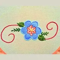 desenho floral bordado à mão em tecido de algodão com flor central bordada em ponto caseado. peça da artesã andrea catão para o canal rosália rosarinha
