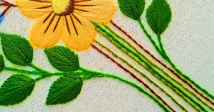 detalhe de bordado da artesã andrea catão de caules de folhas e flores bordadas com o ponto haste